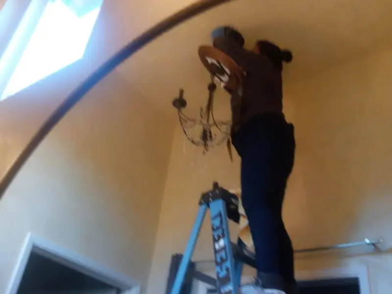Electrician installing a chandelier in a Federal Heights residence